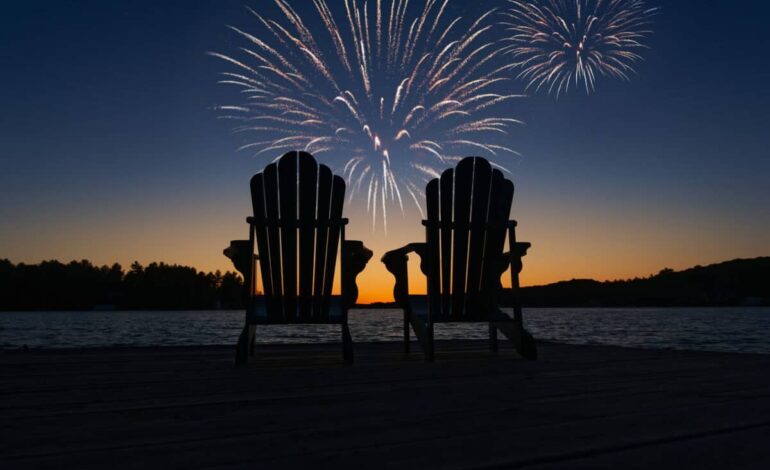 Canada Day fireworks over two Adirondack chairs on the wooden dock in Ontario, Canada