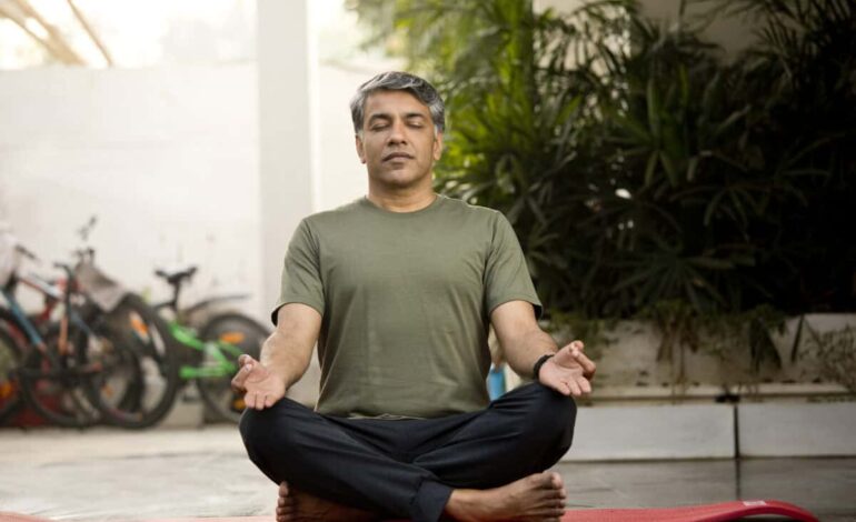 Man meditating in lotus position outdoor on patio